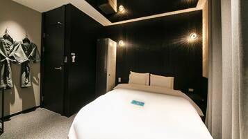 Quarto de hotel moderno com uma cama grande, paredes escuras e luzes de teto embutidas.
