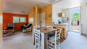 Eine moderne Küche mit Essbereich, Blick ins Freie und einer kleinen Sitzecke mit Sessel und Sofa.