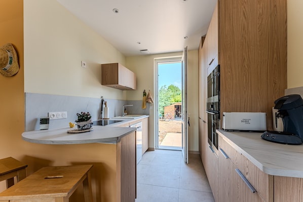 Une cuisine moderne dotée d’un îlot central intégré, de meubles en bois et offrant une vue sur l’extérieur.