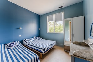 Een kamer met twee bedden, een raam, een deur en een marmeren aanrecht.