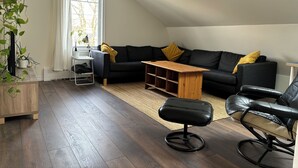 A modern living room with a black sofa, wooden coffee table, and leather armchair.