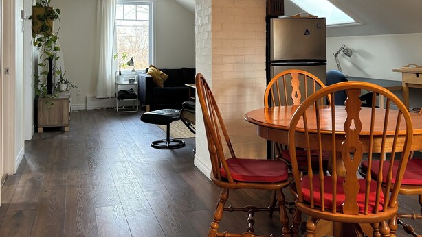 A dining area with a wooden table and chairs, a wall clock, and a star-shaped hanging light fixture.