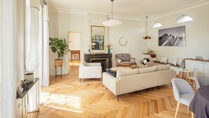 A spacious living room with a herringbone floor, a fireplace, and a large mirror. - Harmonie - Spacious house with pool in Oullins (Oullins-Pierre-Bénite)