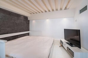 Un dormitorio moderno con cama, televisor y un banco empotrado.