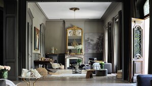 A spacious living room with a fireplace, a large mirror, and a chandelier.