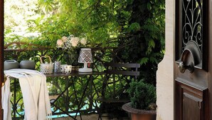 An outdoor patio with a table, chairs, and a potted plant.