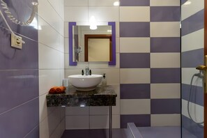Ein Badezimmer mit einem weißen Waschbecken, einem Spiegel und einer Dusche.