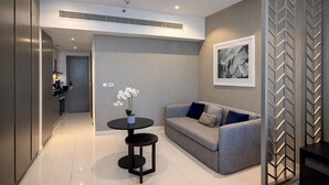 Een modern interieur met een grijze bank, een ronde tafel met een potorkidee, en een zwarte console tafel.