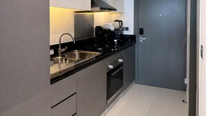 Een moderne keuken met roestvrijstalen apparatuur, een zwart aanrecht en een grijze deur.