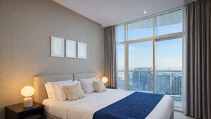 Een moderne hotelkamer met een groot bed, twee nachtkastjes, een uitzicht op de stad door grote ramen en een stadsgezicht buiten.