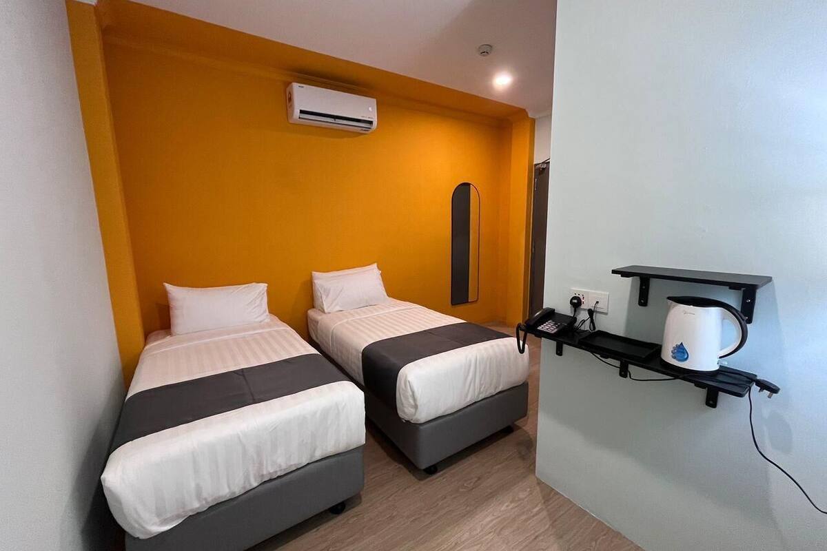 Habitació d'hotel amb dos llits, aire condicionat, un telèfon i una estant amb una tassa.