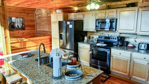 A modern kitchen with granite countertops, stainless steel appliances, and wooden cabinetry. - Starry Night - Awesome Views, Hot Tub, Fire Pit! (Sevierville)