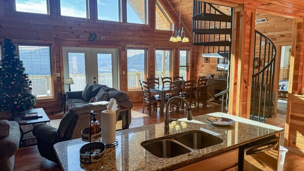 A cozy cabin interior with a dining area, kitchen, and a spiral staircase. - Starry Night - Awesome Views, Hot Tub, Fire Pit! (Sevierville)