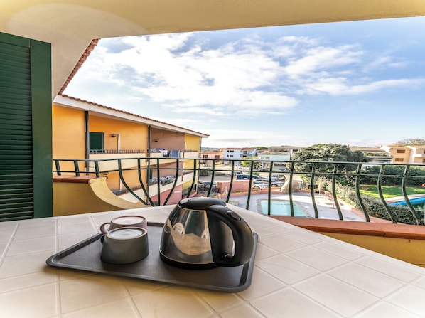Un balcone con vista su una piscina e sugli edifici circostanti.