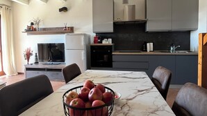 Una cucina moderna con piani di lavoro in marmo, un tavolo da pranzo con sedie e una ciotola di mele.