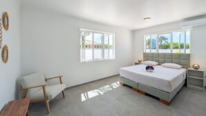 Une chambre à coucher avec un lit, deux tables de chevet, une chaise et une fenêtre.