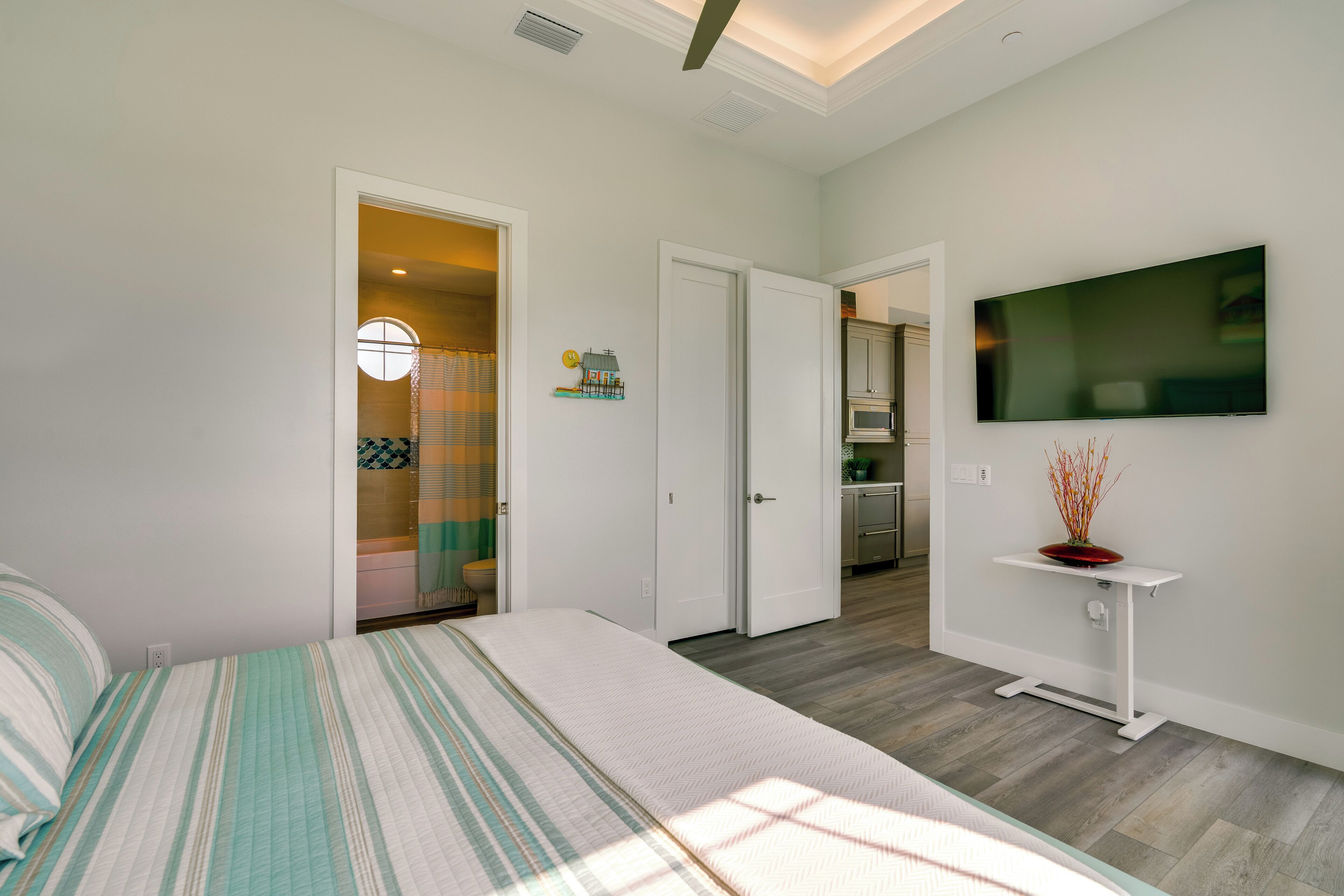 A bedroom with a bed, a TV mounted on the wall, and a door leading to a bathroom.