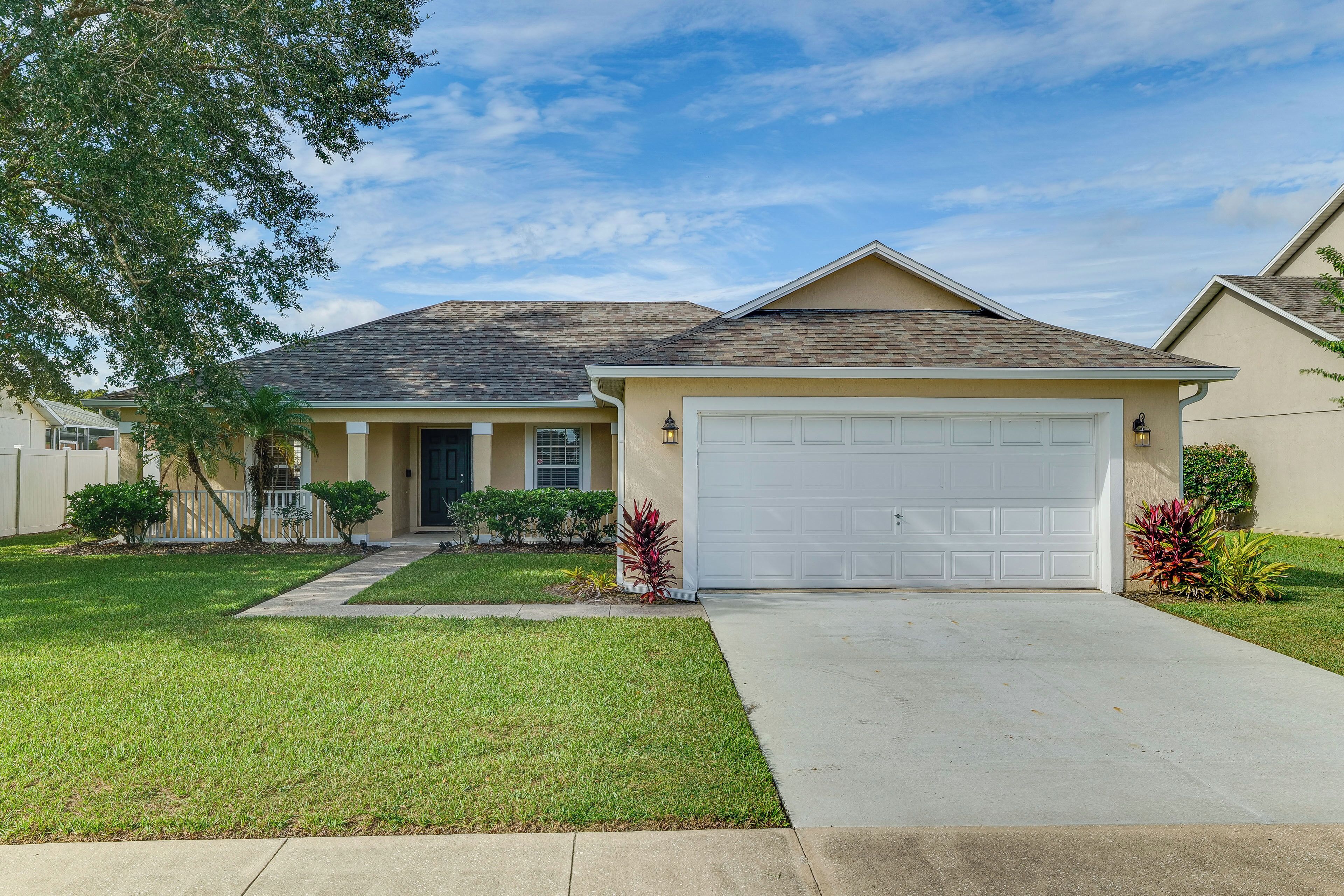 A residential house with a front garage, a well-maintained lawn, and a clear sky.