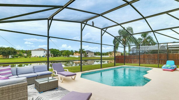 Un espacio al aire libre techado con piscina, sillones de descanso y un sofá.