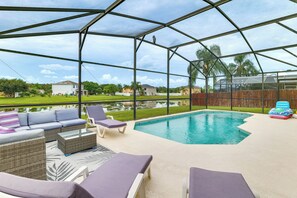 A covered outdoor area with a pool, lounge chairs, and a sofa. - Florida Family Fun! Tranquil Home w/ Water Views (Kissimmee)