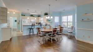 A spacious kitchen with a dining area, featuring a large wooden table and chairs, light blue walls, and a view of the outdoors through the windows. - Screened Patio w/ Pond Views! Myrtle Beach Condo (Myrtle Beach)