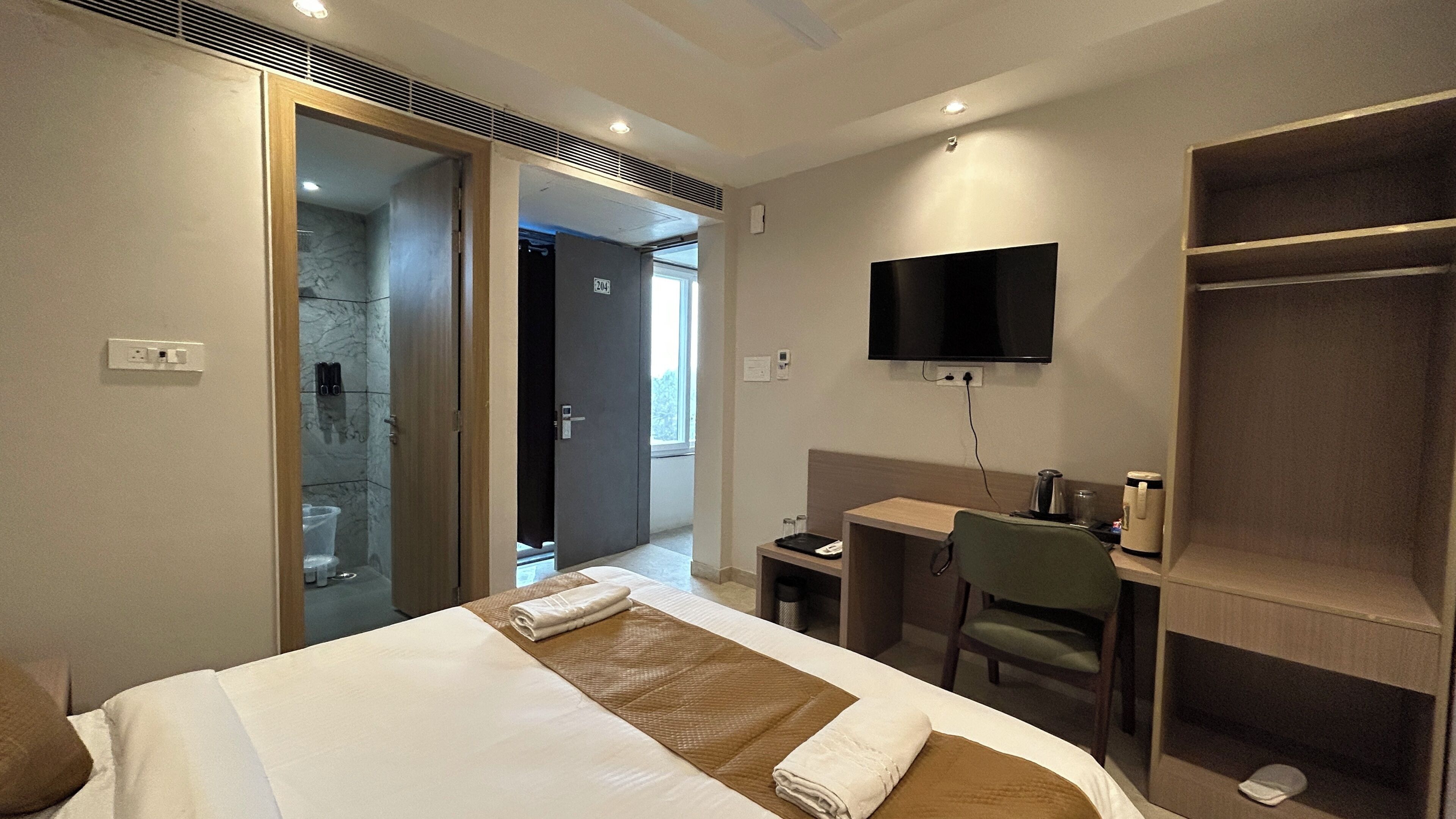 Ein Hotelzimmer mit einem Bett, einem Schreibtisch, einem Sessel, einem Fernseher und einem Kleiderschrank.