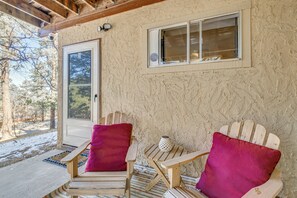 Eine Holzterrasse mit zwei Adirondack-Stühlen und einer Tür.