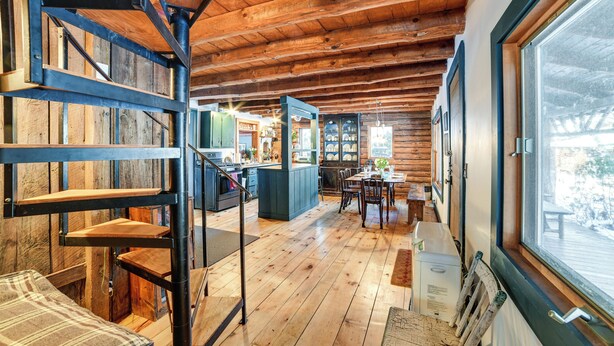 Un intérieur spacieux en bois, doté d’un escalier, d’un coin repas et d’une grande fenêtre offrant une vue sur l’extérieur.