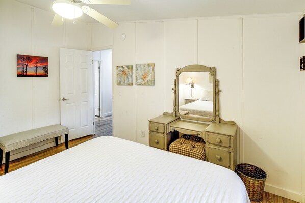 A bedroom with a bed, a bench, a dresser with drawers, a mirror, and wall art. - Butler Home Near Watauga Lake w/ Furnished Patio! (Butler)