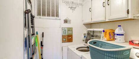 A laundry room with a washing machine, a drying rack, and a chandelier.