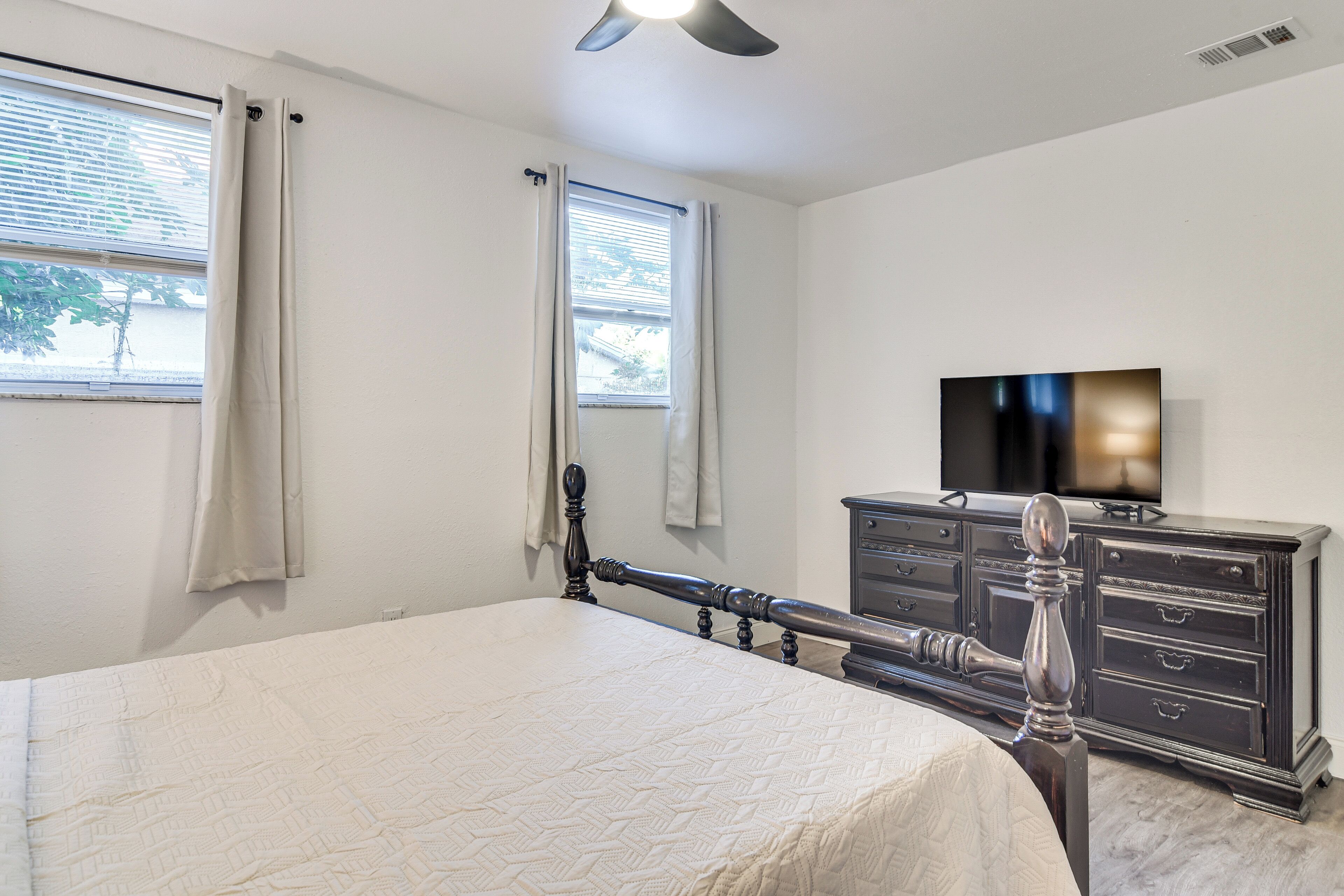 A bedroom with a bed, a dresser, and a television.