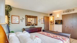A neatly made bed with white linens and a patterned blanket, a wooden dresser with a mirror, a television mounted on the wall, and a door leading to another room. - Half-mi to Loop Access! Private Tucson Hideaway (Tucson)
