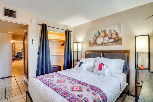A hotel room with a large bed, a headboard, a painting on the wall, and a desk with a lamp. - Half-mi to Loop Access! Private Tucson Hideaway (Tucson)