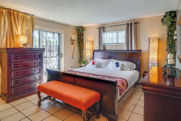 Una camera da letto con un letto di legno, una panca, una cassettiera e una finestra con tende.