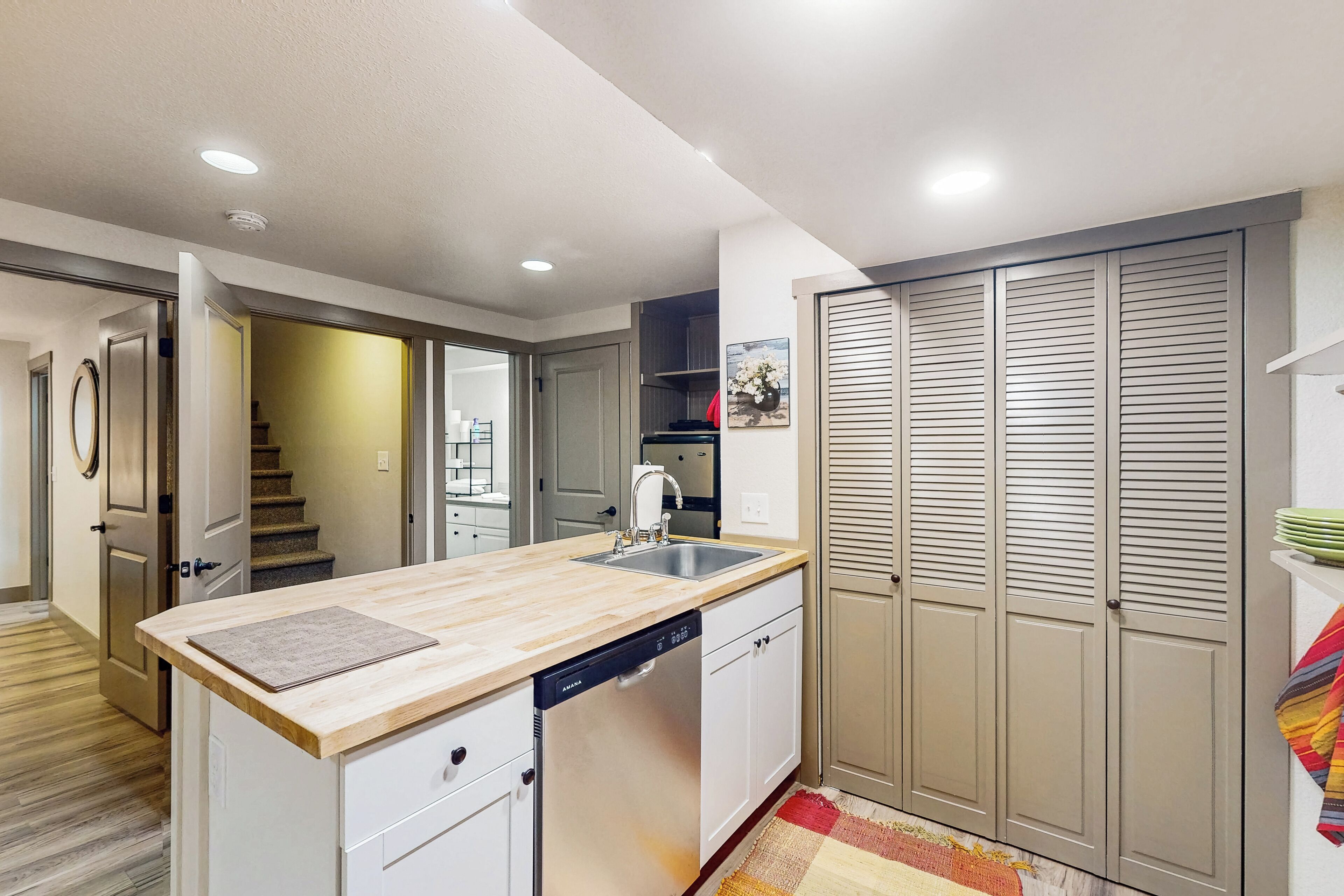 Cozinha moderna com bancada de madeira, lava-louças embutida e um amplo closet com portas deslizantes.