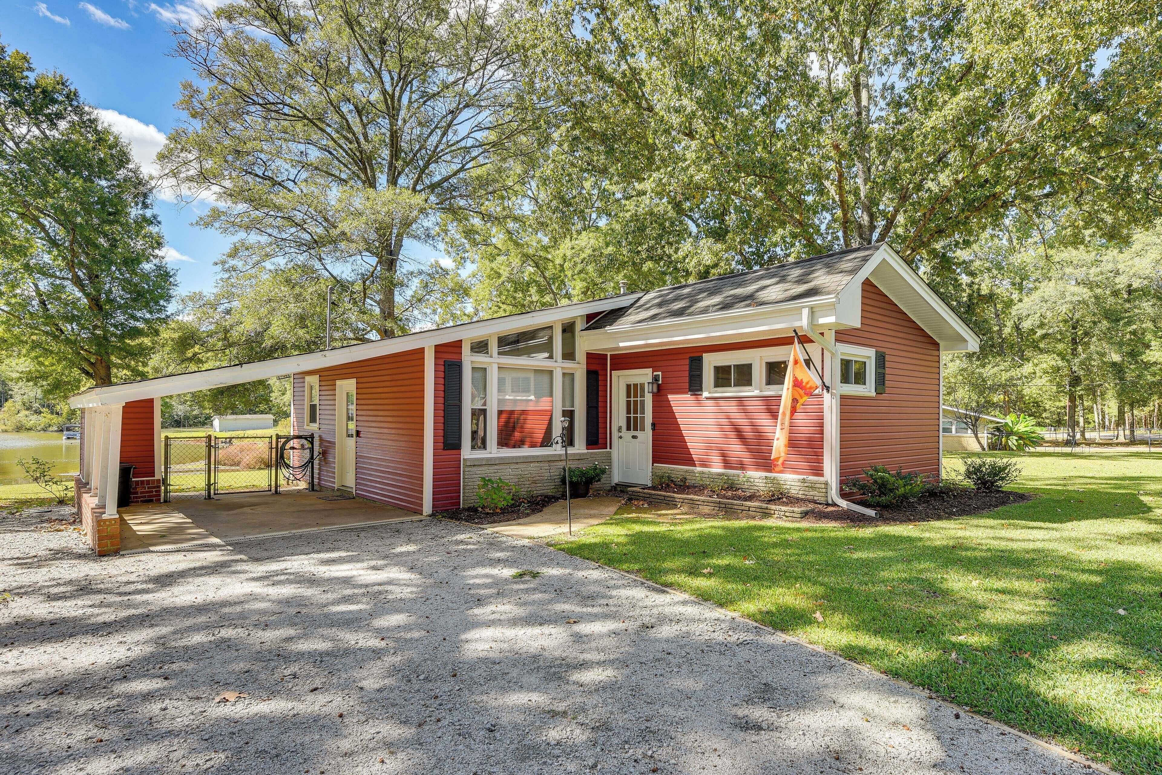 A red single-story house with a covered porch, a small front yard, and a flagpole.