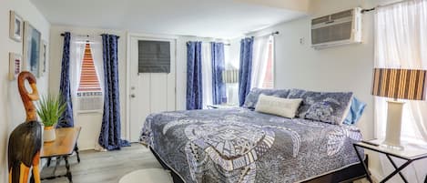 Un dormitorio con cama, cortinas, una planta, una guitarra y una ventana.