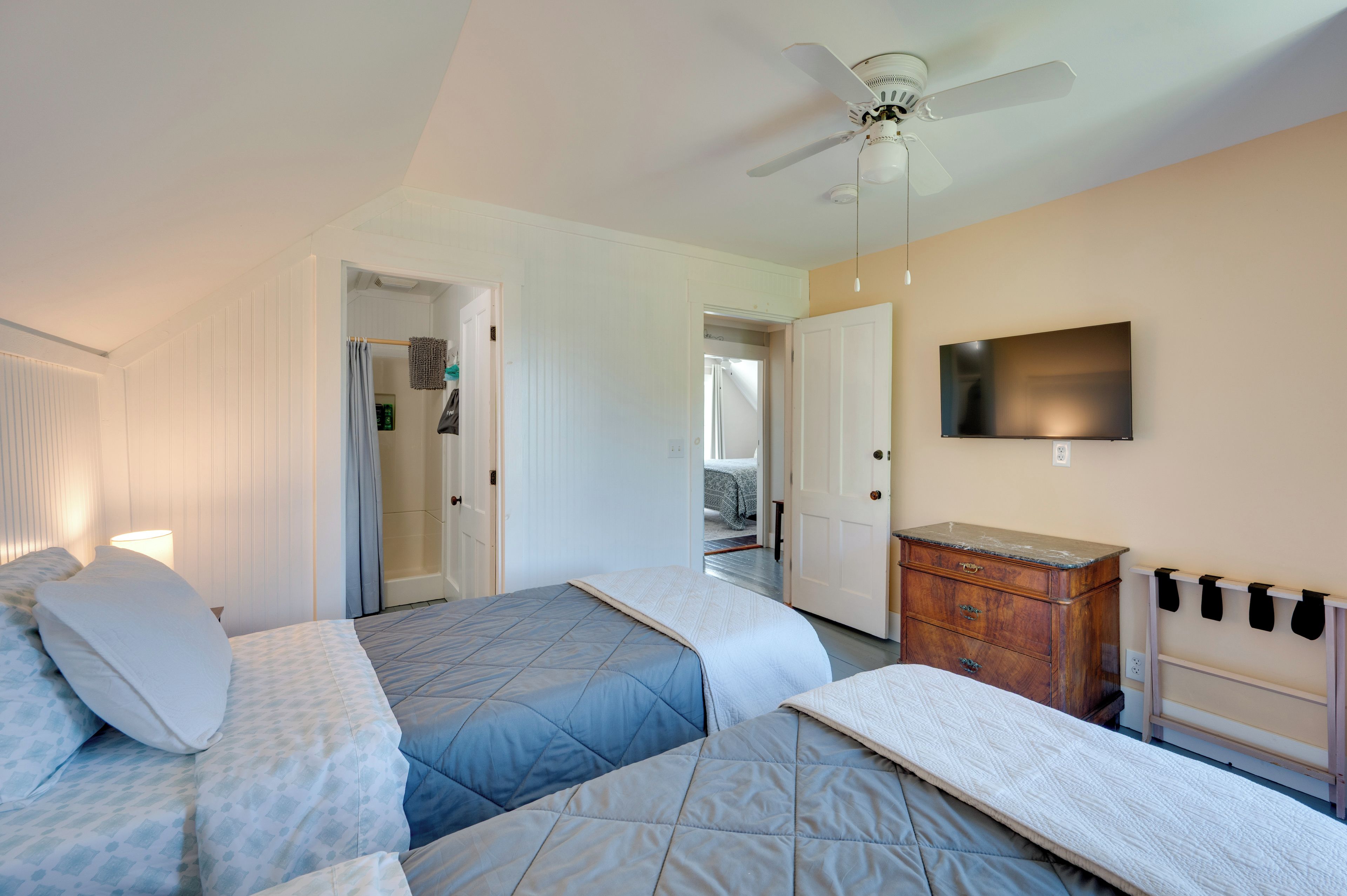 Une chambre d’hôtel équipée d’un lit, d’une télévision, d’un ventilateur de plafond et d’une commode.