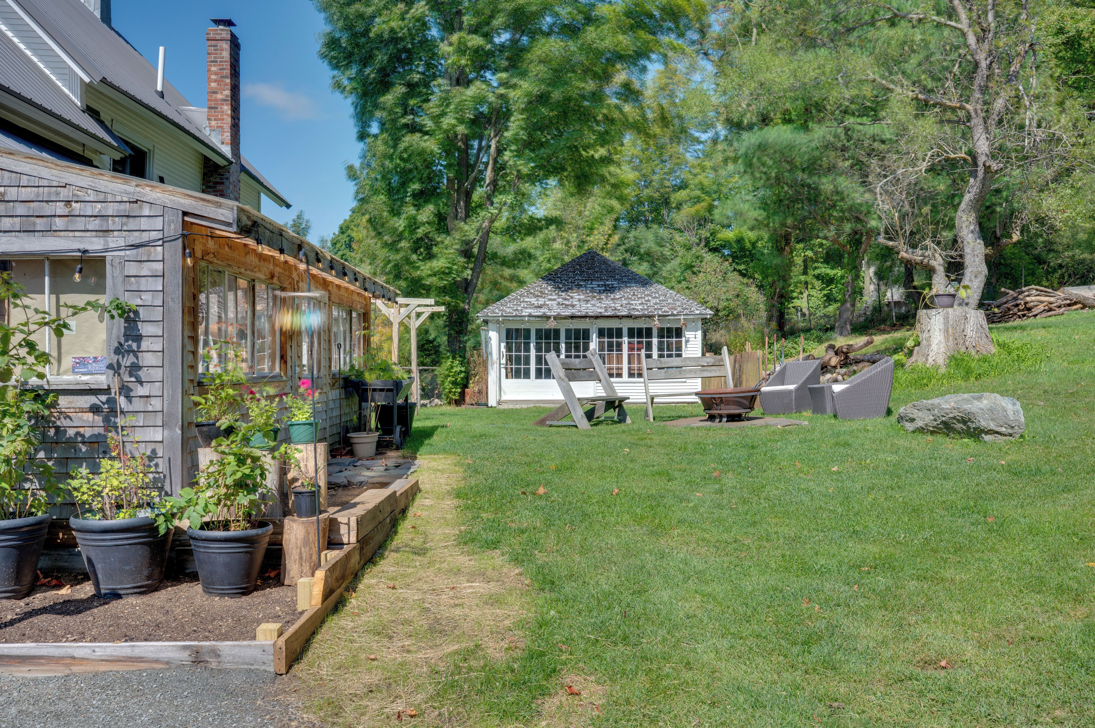A house with a covered porch, a small shed, and a grassy yard with trees.