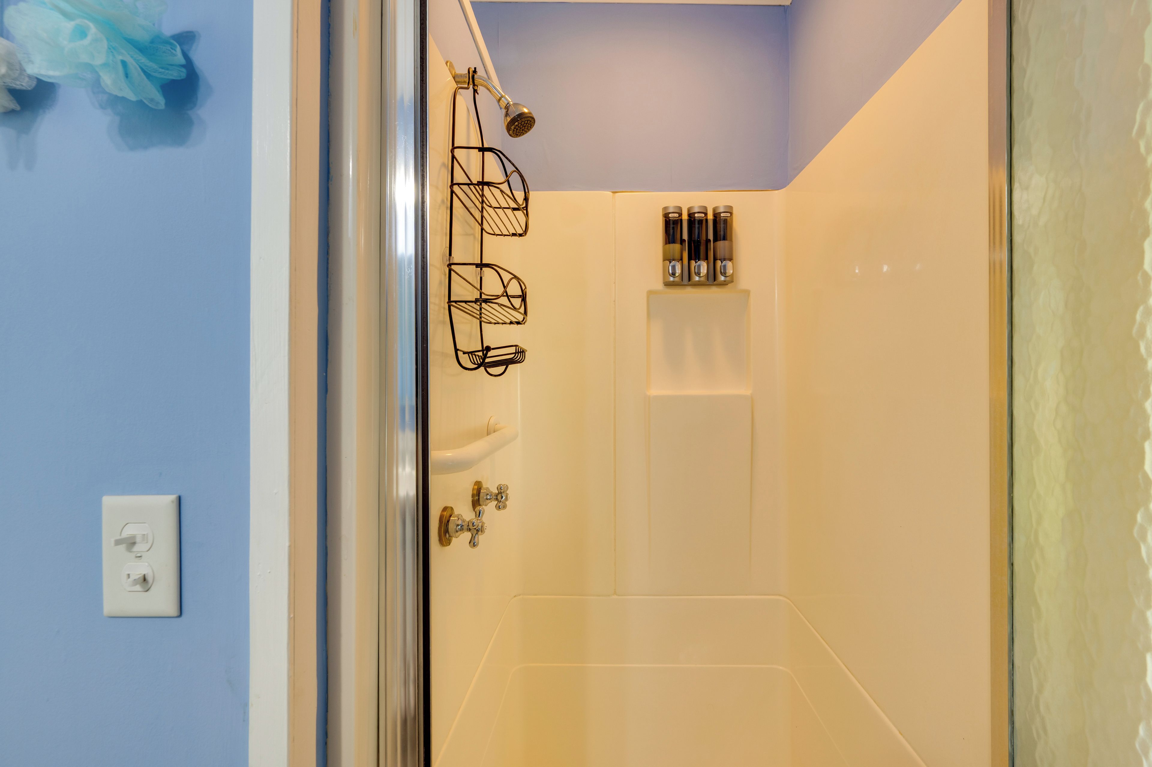A bathroom with a glass shower door, a white sink, and a towel rack.