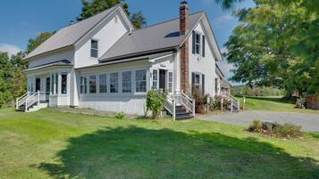 Une maison à deux étages avec un porche, une cheminée et une pelouse bien entretenue.