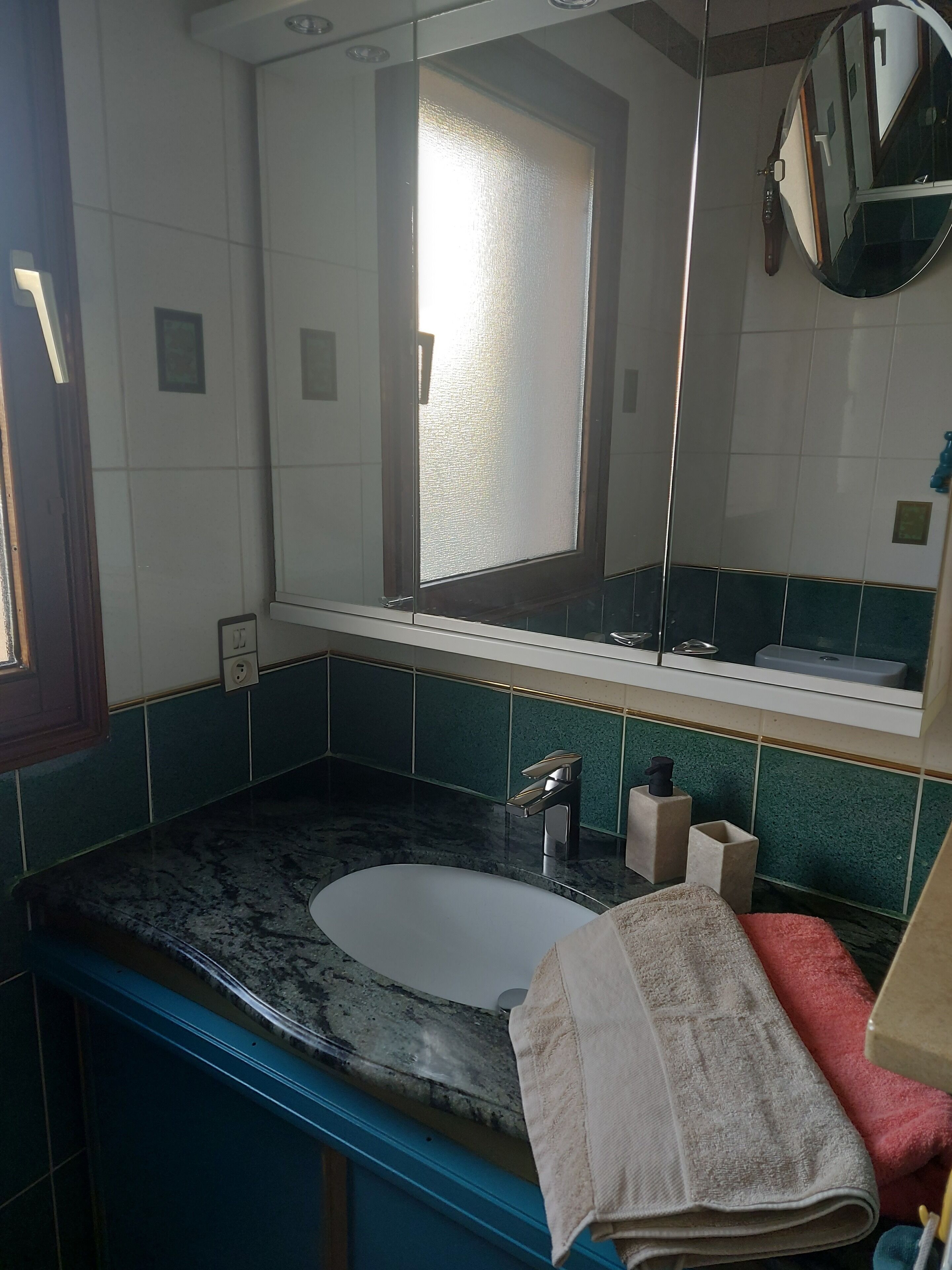 Une salle de bain avec un lavabo en marbre, un miroir et une fenêtre.