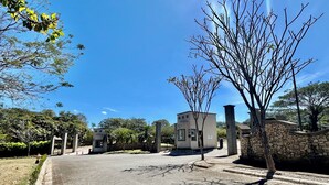 A paved street with a stone wall on one side and a building with a flat roof and a small entrance. - Villa Continental-Ideal for families-Strategic location in Nicoya Guanacaste (Nicoya)
