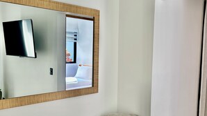 A modern room with a large mirror, a grey armchair, a small round wooden table, and a white wardrobe. - Villa Continental-Ideal for families-Strategic location in Nicoya Guanacaste (Nicoya)