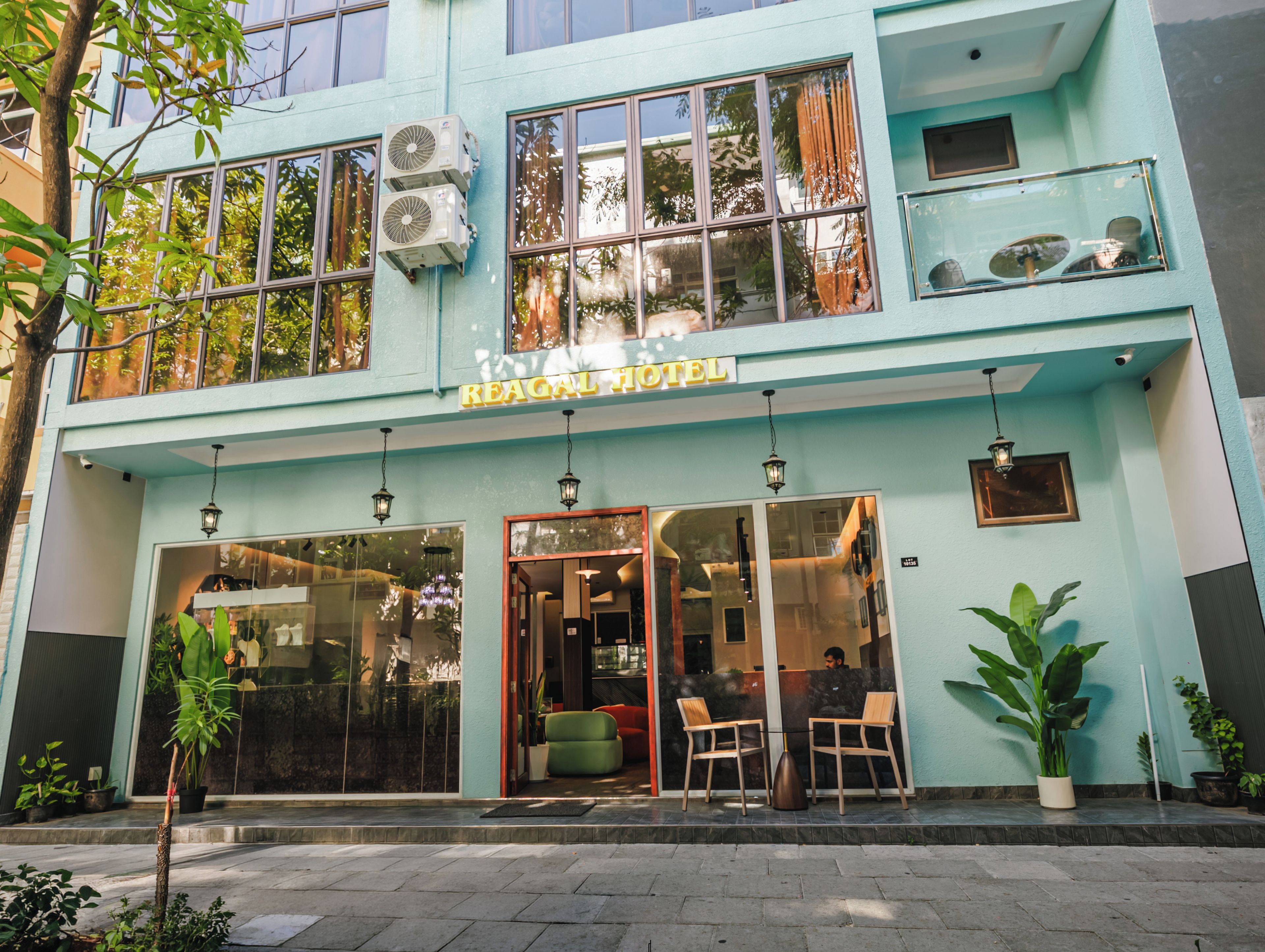 A hotel with a modern design, featuring a large glass entrance, outdoor seating, and a sign that reads 'REAGAL HOTEL'.