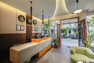 Zona de recepción con mostrador, un reloj, certificados enmarcados y vistas de la calle.