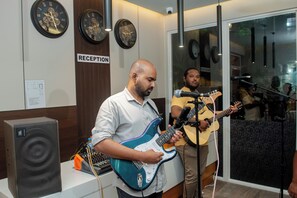 Un área de recepción con relojes en la pared, un micrófono y un guitarrista.