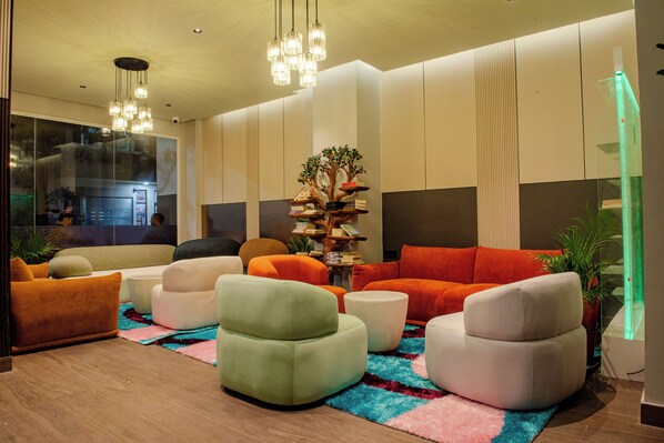Una sala moderna con sofás y sillones, un árbol decorativo y un ventanal grande.
