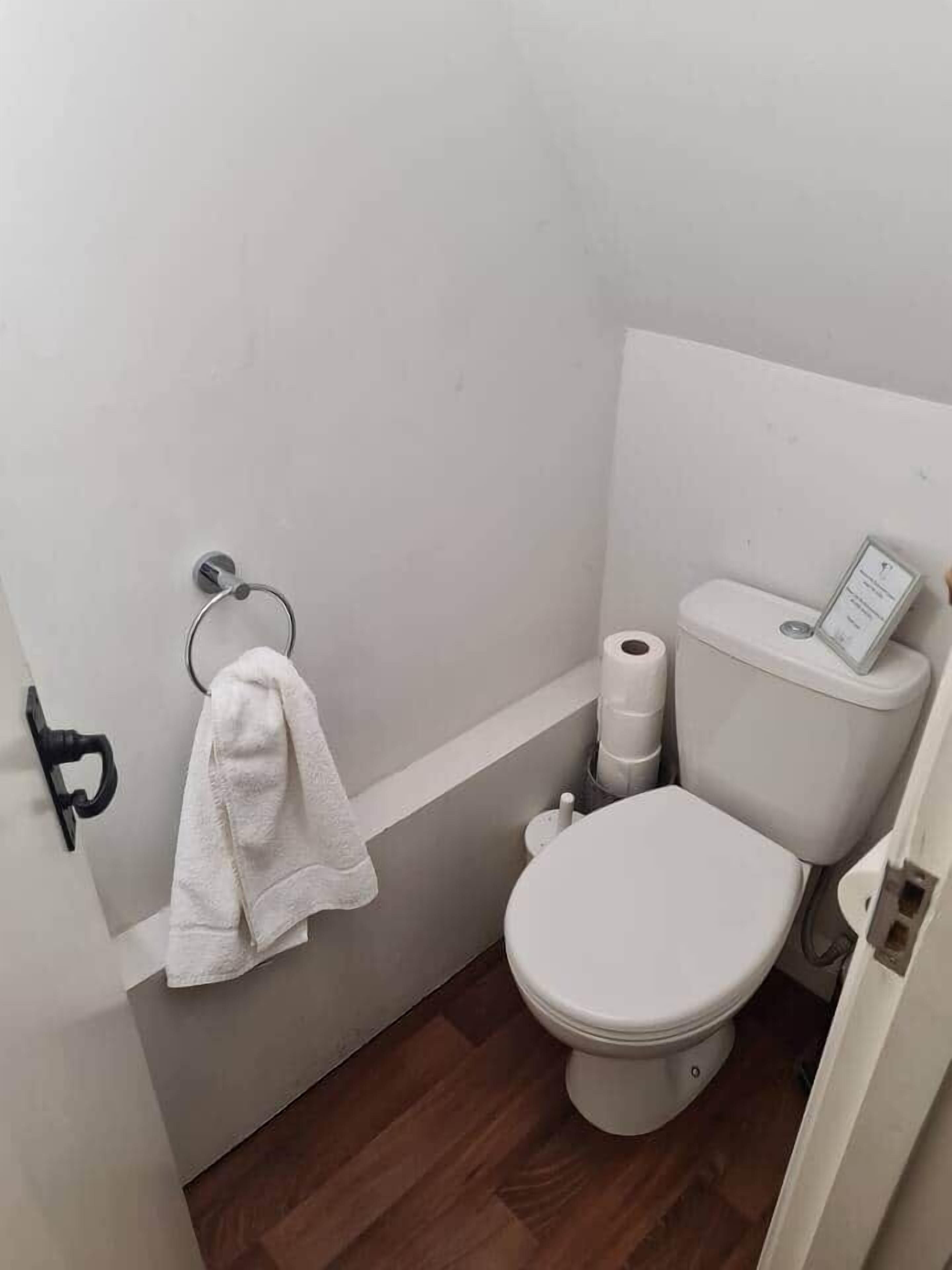 A small bathroom with a toilet, a towel rack, and a toilet paper holder.