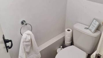 A small bathroom with a toilet, a towel rack, and a toilet paper holder.
